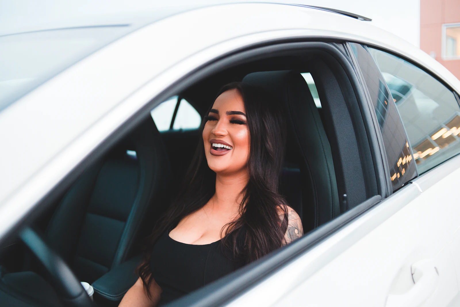 A smiling woman at the wheel of a white car